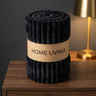 Rolled black ribbed fleece AC blanket with a Home Living label