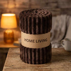 Rolled brown ribbed fleece AC blanket with a Home Living label