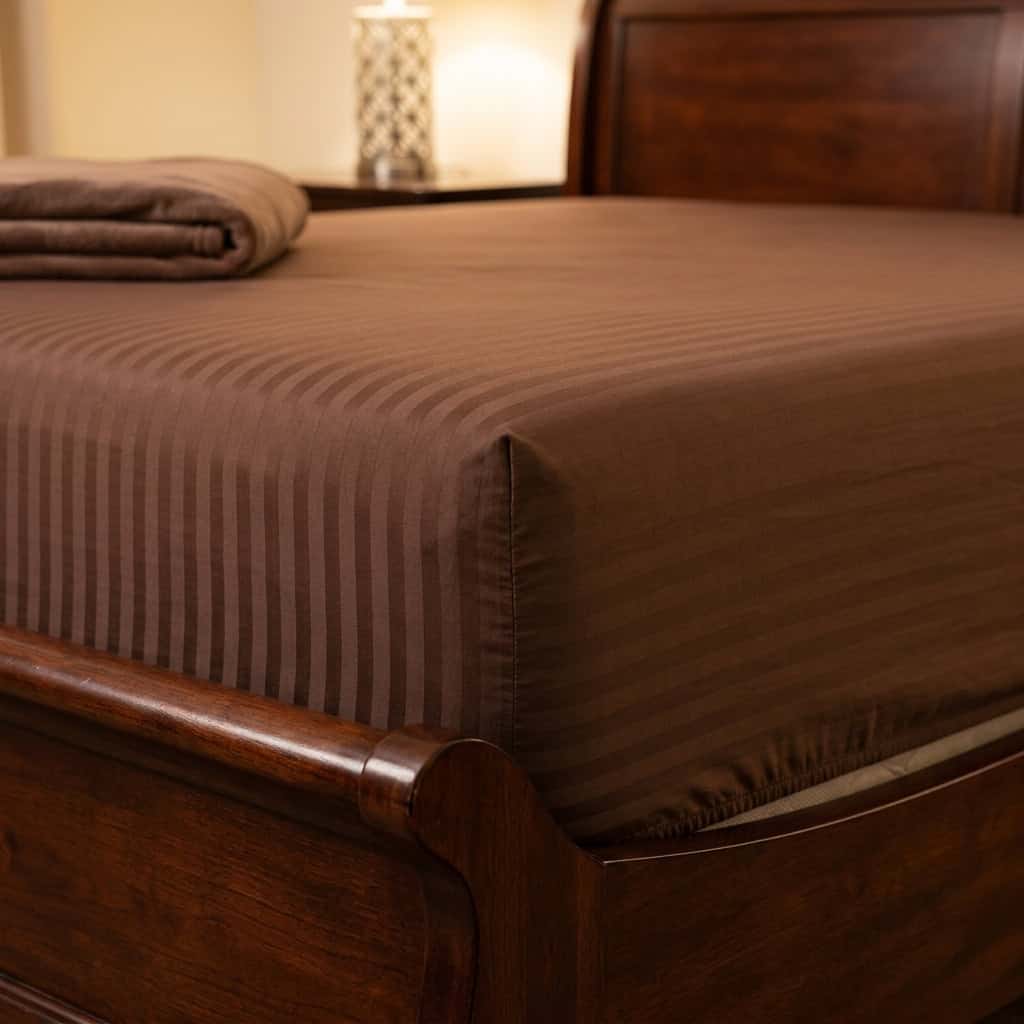Chocolate brown fitted sheet with elastic sides around a mattress corner
