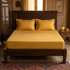 Mustard cotton fitted bedsheet with 2 pillow covers on a king size bed