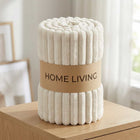Rolled off-white ribbed fleece AC blanket with a Home Living label